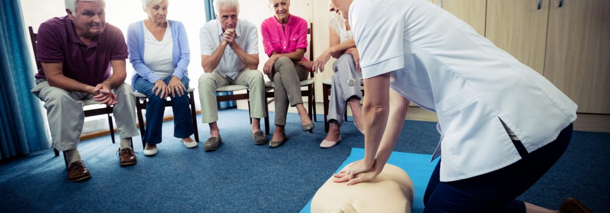 Nurse teaching first aid to a group of seniors in the retirement house