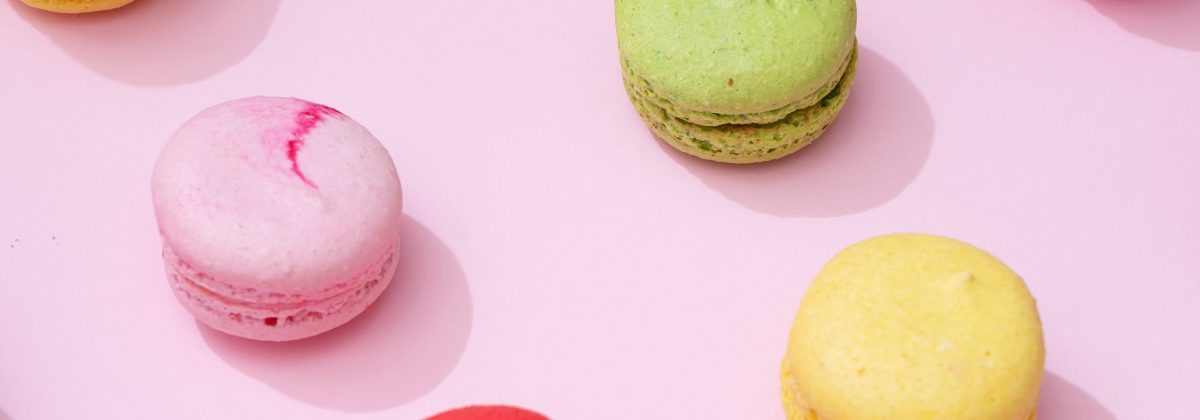 Pastel pink table top with colorful macarons pattern. Minimal sweet food concept. Cookie concept.
